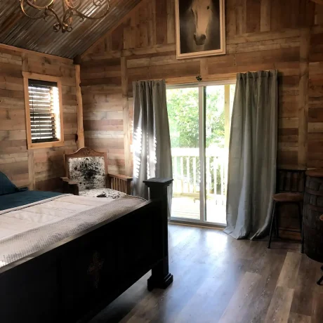 A cozy, wooden cabin nestled in a scenic setting with the sun setting behind it, emphasizing the rustic charm and peaceful atmosphere at Oak Meadow Ranch RV in Valley View, TX.