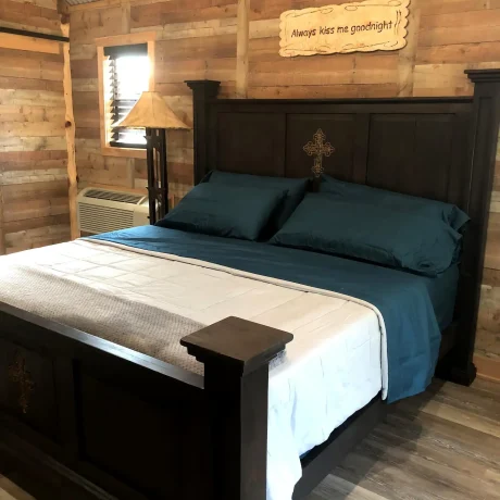 A cozy, wooden cabin nestled in a scenic setting with the sun setting behind it, emphasizing the rustic charm and peaceful atmosphere at Oak Meadow Ranch RV in Valley View, TX.