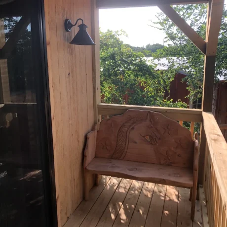 A cozy, wooden cabin nestled in a scenic setting with the sun setting behind it, emphasizing the rustic charm and peaceful atmosphere at Oak Meadow Ranch RV in Valley View, TX.