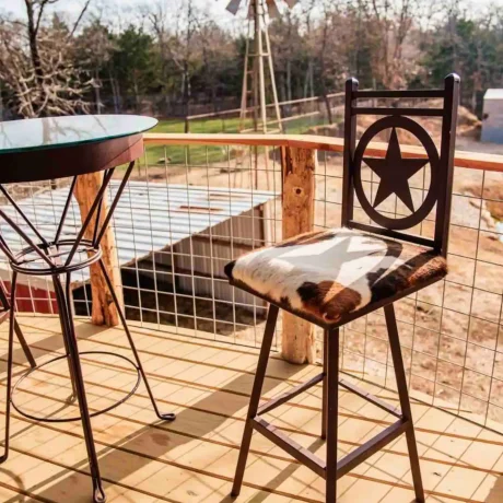 A cozy, wooden cabin nestled in a scenic setting with the sun setting behind it, emphasizing the rustic charm and peaceful atmosphere at Oak Meadow Ranch RV in Valley View, TX.