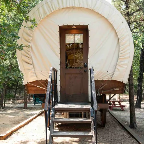 A cozy, spacious Conestoga Wagon with access to pool and hot tub, offering a unique, rustic farm stay experience at Oak Meadow Ranh RV in Valley View, TX.