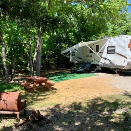 Picturesque RV sites nestled among shady oak trees with tranquil, spacious surroundings, fire pits, and picnic tables at Oak Meadow Ranch in Valley View, TX.